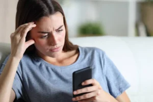 נערה מתבוננת במבט מוטרד במסך הטלפון שלה