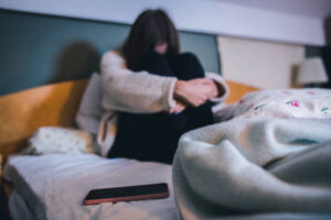 Sad teen with a phone in her bedroom